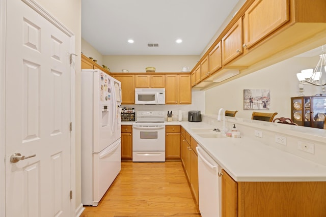 kitchen with sink, a chandelier, light wood-type flooring, kitchen peninsula, and white appliances