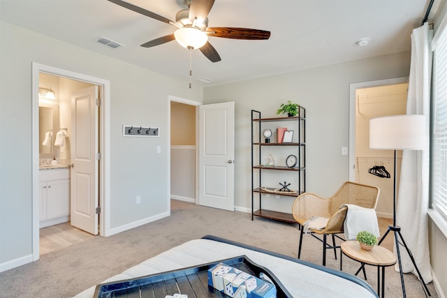 bedroom featuring ceiling fan, ensuite bath, and light carpet