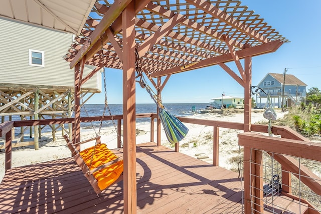 view of dock featuring a deck with water view, a beach view, and a pergola