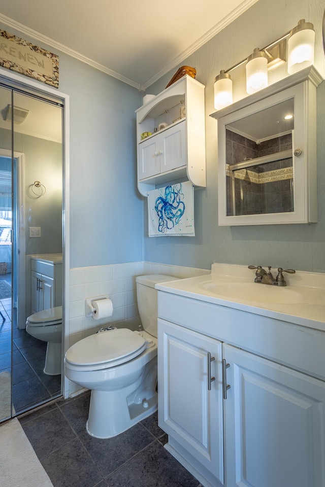 bathroom featuring tile patterned flooring, vanity, crown molding, toilet, and tile walls