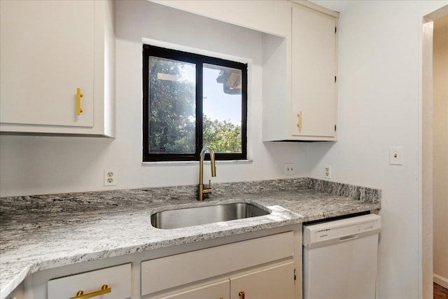 kitchen featuring white cabinetry, light stone countertops, a sink, and white dishwasher