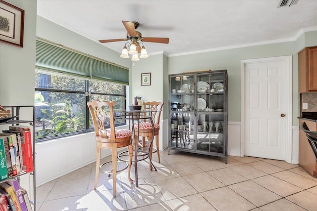 dining area with light tile patterned floors, visible vents, ornamental molding, and a ceiling fan