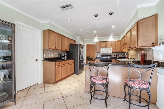 kitchen featuring visible vents, range, stainless steel fridge with ice dispenser, white microwave, and hanging light fixtures