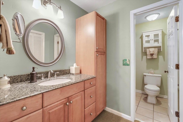 bathroom featuring tile patterned flooring, baseboards, vanity, and toilet