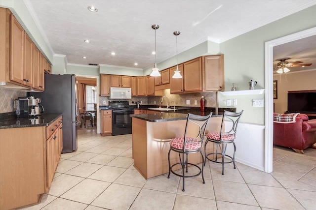 kitchen featuring white microwave, a peninsula, black range with electric cooktop, pendant lighting, and a sink