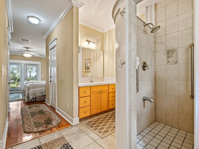 bathroom featuring vanity, crown molding, tile patterned flooring, ceiling fan, and a tile shower