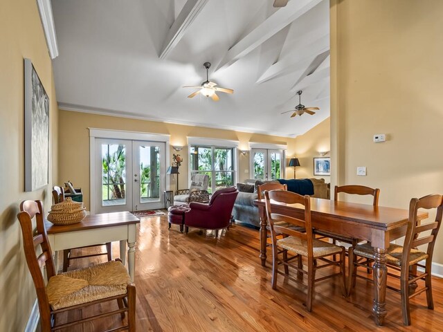 dining space featuring vaulted ceiling, light hardwood / wood-style floors, ornamental molding, and french doors