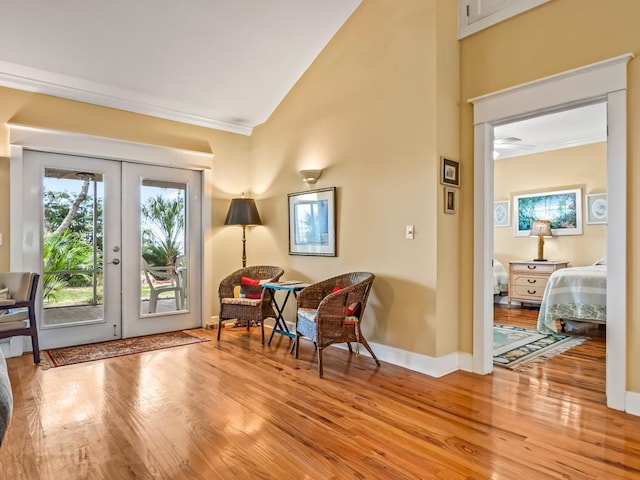 living area featuring vaulted ceiling, french doors, crown molding, and light hardwood / wood-style flooring