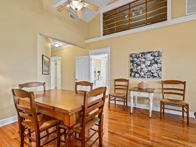 dining area featuring ceiling fan, light hardwood / wood-style flooring, high vaulted ceiling, and ornamental molding