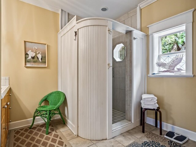 bathroom with a tile shower, tile patterned floors, and vanity