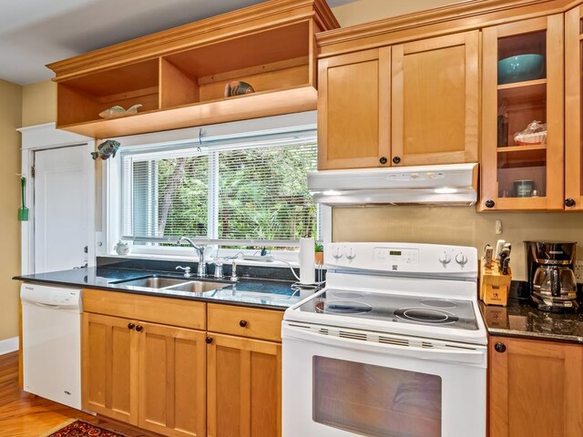 kitchen with wood-type flooring, white appliances, dark stone countertops, and sink