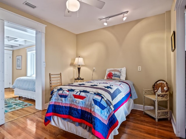 bedroom with ceiling fan, wood-type flooring, and rail lighting