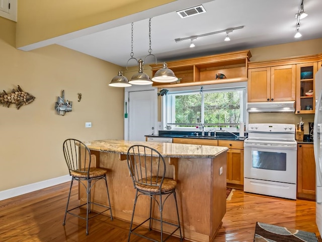 kitchen with sink, light wood-type flooring, white range with electric stovetop, a kitchen island, and light stone counters