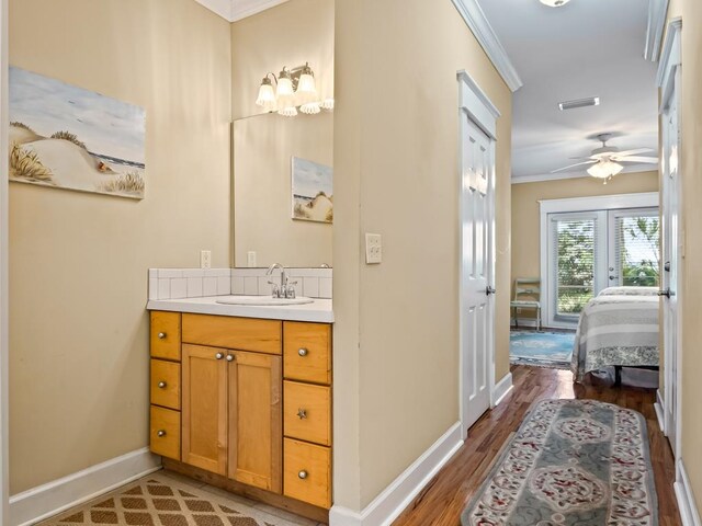 bathroom with ceiling fan, hardwood / wood-style floors, vanity, and ornamental molding