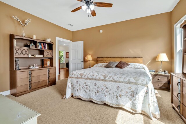 carpeted bedroom featuring ceiling fan and multiple windows