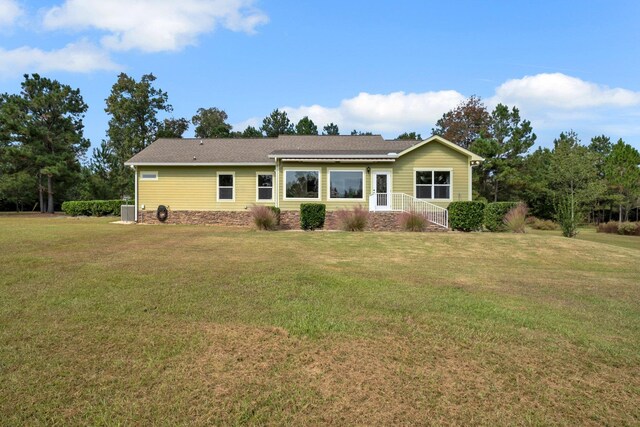 back of house featuring central AC unit and a lawn