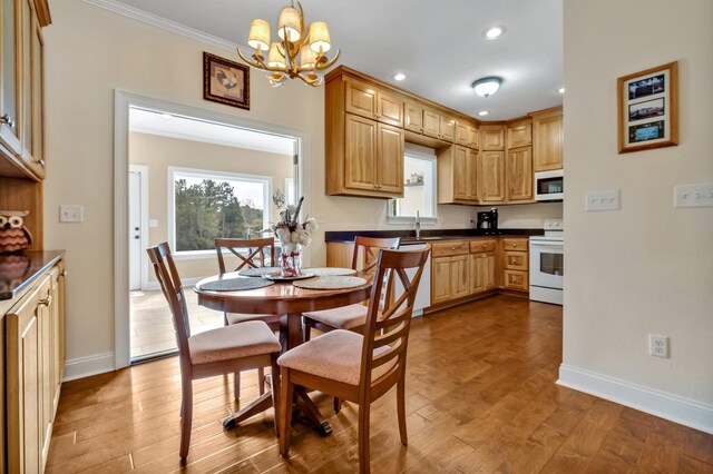 kitchen with crown molding, a notable chandelier, pendant lighting, white appliances, and light hardwood / wood-style flooring