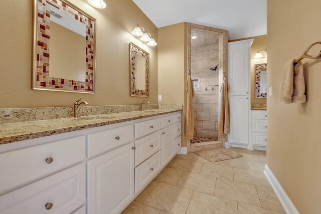 bathroom featuring tile patterned flooring, vanity, and a tile shower