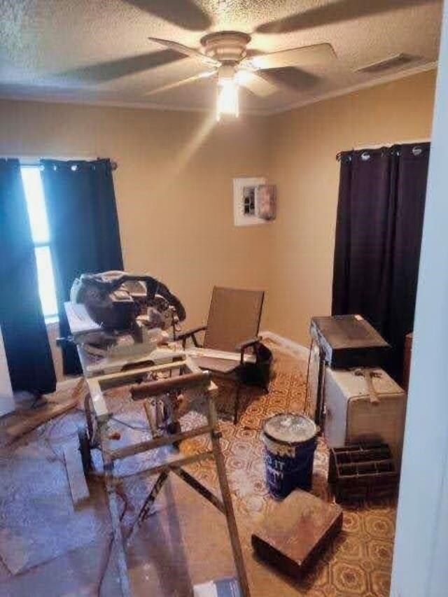 interior space featuring a textured ceiling, ceiling fan, and crown molding