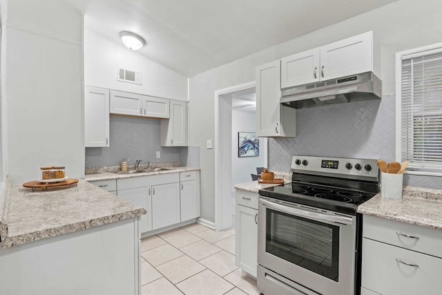 kitchen with vaulted ceiling, sink, electric range, white cabinetry, and light tile patterned flooring