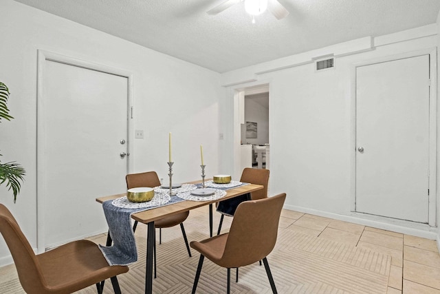 tiled dining area with ceiling fan and a textured ceiling