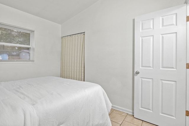 tiled bedroom featuring vaulted ceiling