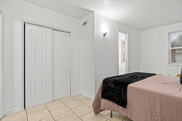 bedroom with light tile patterned flooring, a textured ceiling, and a closet