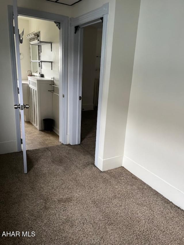 corridor featuring light carpet and baseboards