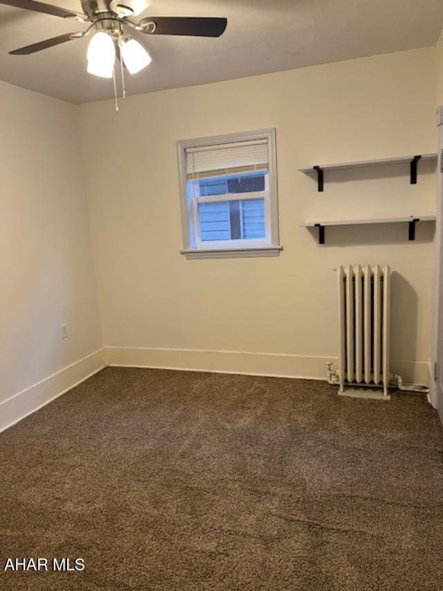 unfurnished room featuring radiator, dark carpet, baseboards, and ceiling fan