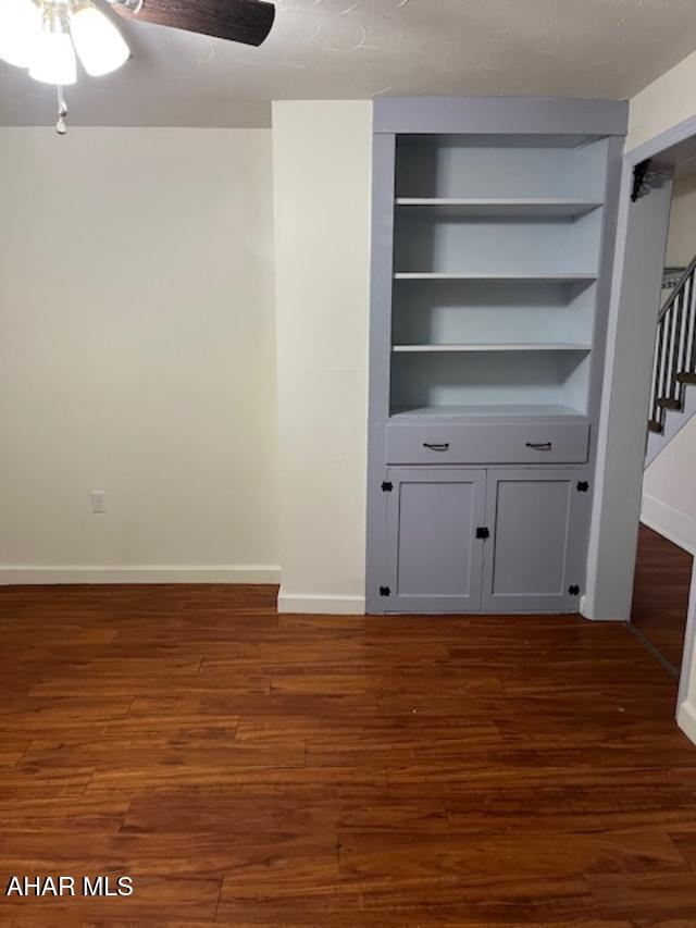 interior space with stairs, dark wood-type flooring, a ceiling fan, and baseboards