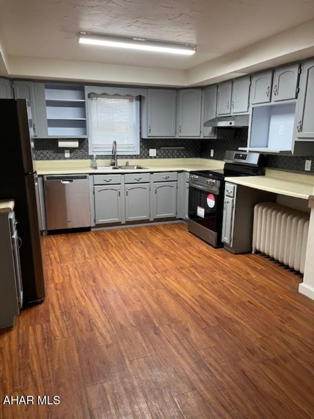 kitchen with a sink, appliances with stainless steel finishes, gray cabinets, and under cabinet range hood