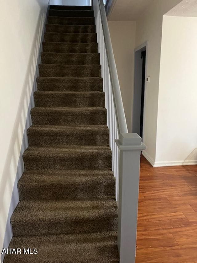 stairway featuring baseboards and wood finished floors