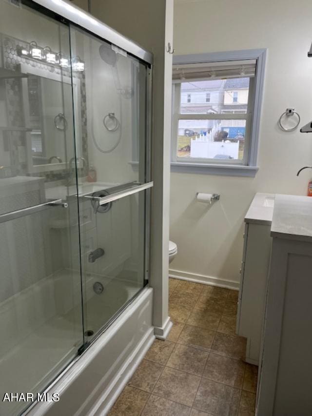 bathroom with toilet, baseboards, combined bath / shower with glass door, and vanity