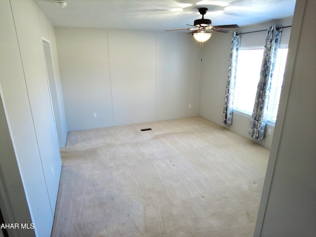 carpeted empty room featuring ceiling fan and a textured ceiling