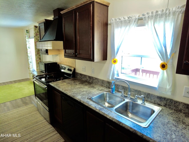 kitchen with custom exhaust hood, black appliances, sink, light hardwood / wood-style flooring, and dark brown cabinetry