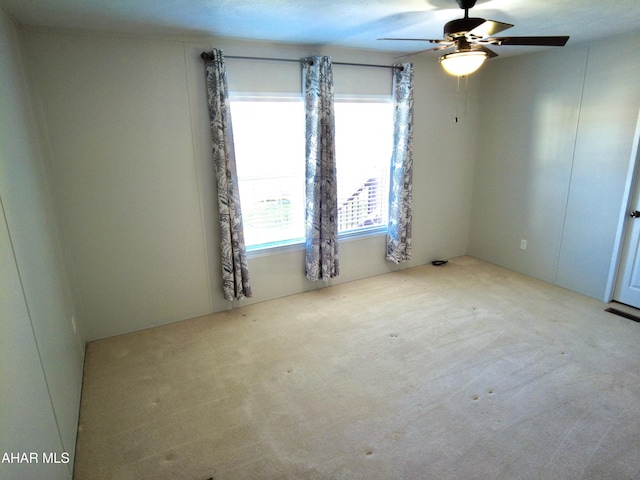 empty room featuring a textured ceiling, light colored carpet, and ceiling fan