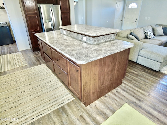 kitchen featuring a center island, stainless steel fridge, washer / clothes dryer, and light hardwood / wood-style flooring