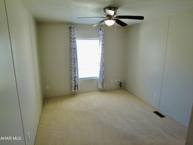 carpeted spare room featuring ceiling fan