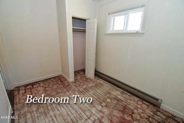 unfurnished bedroom featuring a baseboard radiator and a closet