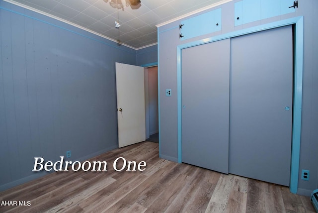 unfurnished bedroom with ornamental molding, wood-type flooring, and a closet