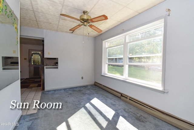 carpeted spare room featuring a baseboard heating unit and ceiling fan