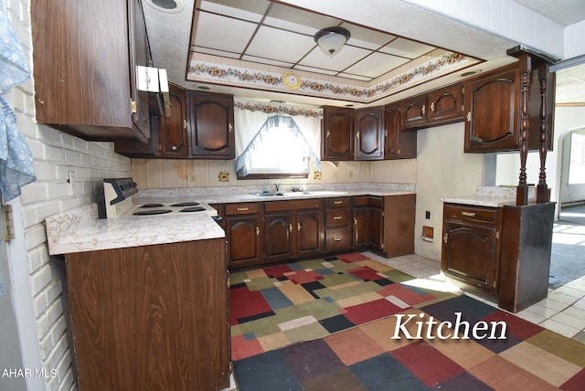 kitchen with electric stove, sink, light tile patterned floors, and dark brown cabinetry