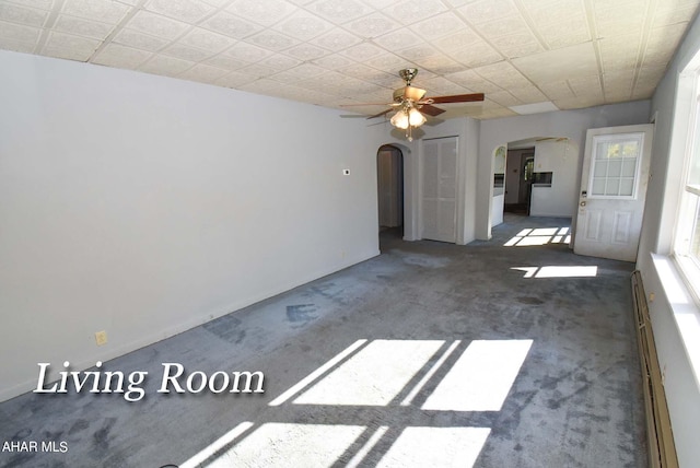 unfurnished living room with dark colored carpet, a baseboard heating unit, and ceiling fan