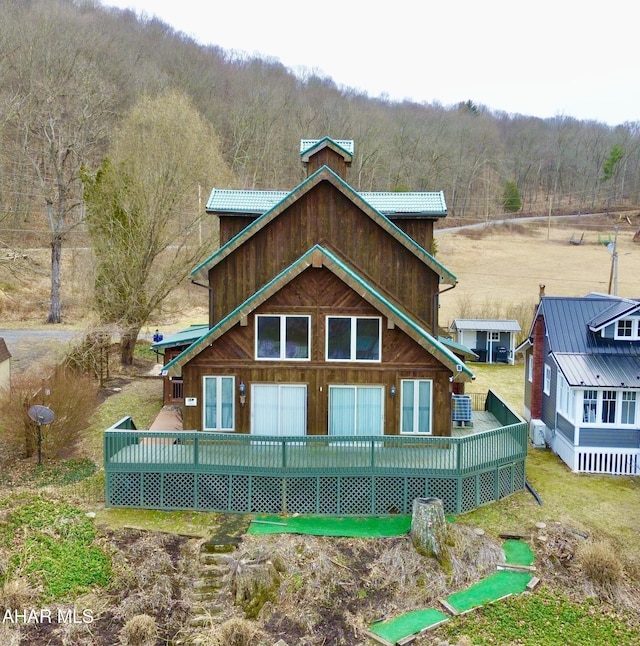 rear view of house with a forest view and a wooden deck