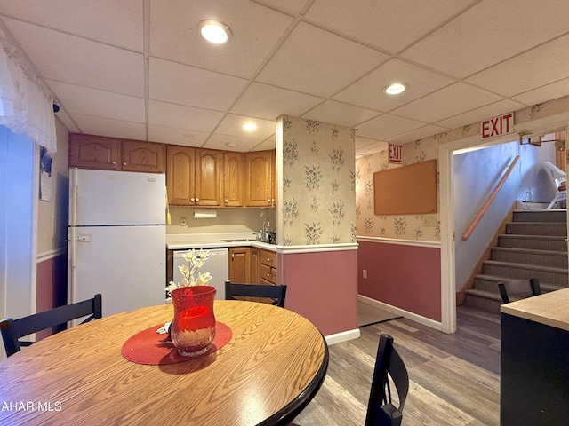 dining room featuring light hardwood / wood-style floors, a drop ceiling, and sink