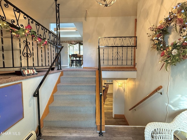 stairway with hardwood / wood-style floors and a baseboard heating unit