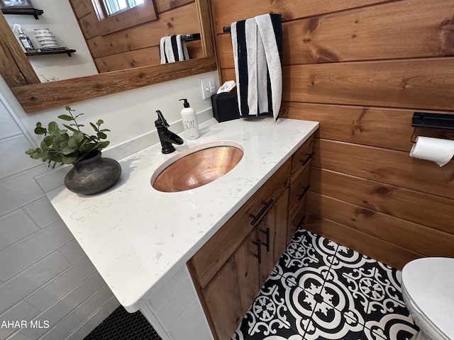 bathroom featuring wooden walls, vanity, and toilet