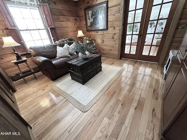 living room featuring wooden walls, french doors, and light wood-type flooring