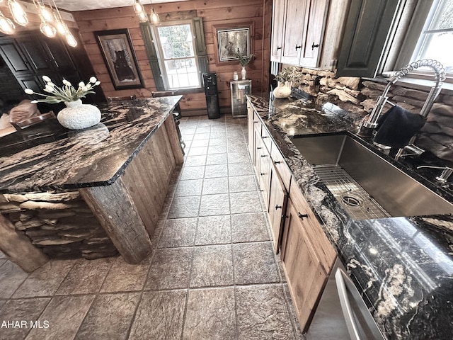 kitchen with dark stone counters, wooden walls, and sink