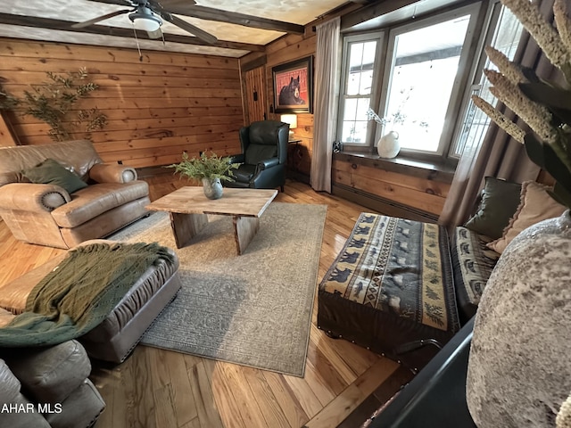 living area with beamed ceiling, light wood-type flooring, and wood walls